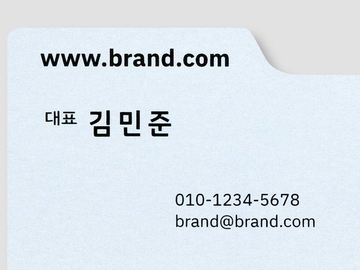 자동차 모양으로 재단한 하늘색 명함의 각진 외곽과 곡선 외곽 접사