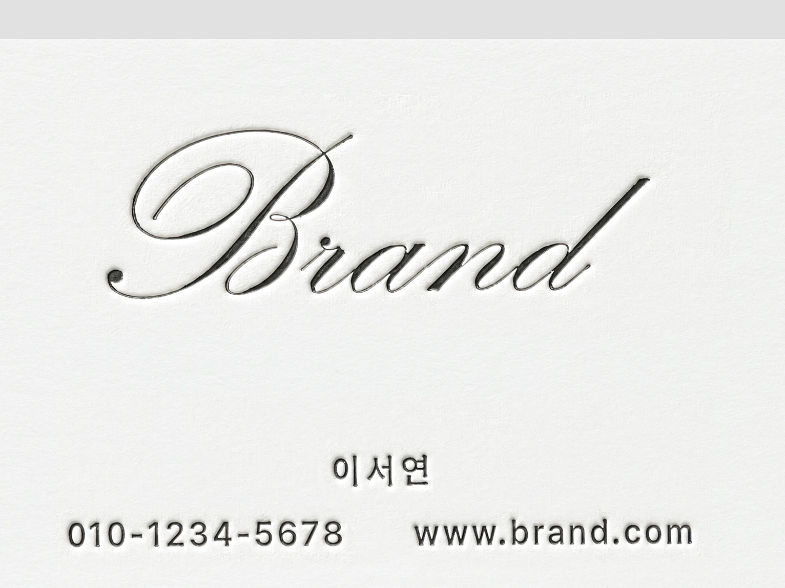 필기체 Brand 로고가 종이에 깊게 눌려 인쇄된 레터프레스 명함 접사